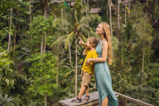 Mom and son on the rice field in the background of rice terraces, Ubud, Bali, Indonesia. Traveling with children concept. Teaching children in practice.