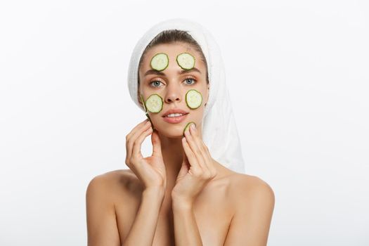 Woman with facial mask and cucumber slices in her hands on white background.