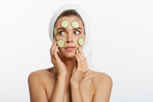 Woman with facial mask and cucumber slices in her hands on white background.