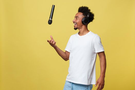 Young handsome African American Male Singer Performing with Microphone. Isolated over yellow gold background