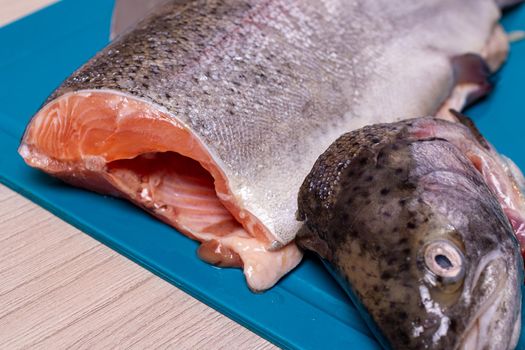 Fresh freshwater trout fish on a bright chopping board and on a wooden background