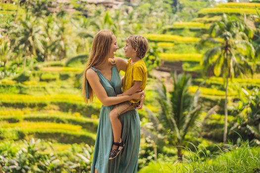 Mom and son on the rice field in the background of rice terraces, Ubud, Bali, Indonesia. Traveling with children concept. Teaching children in practice.