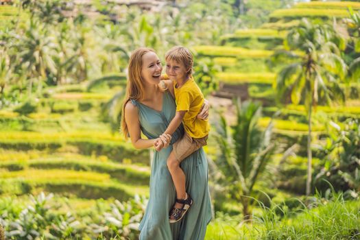 Mom and son on the rice field in the background of rice terraces, Ubud, Bali, Indonesia. Traveling with children concept. Teaching children in practice.