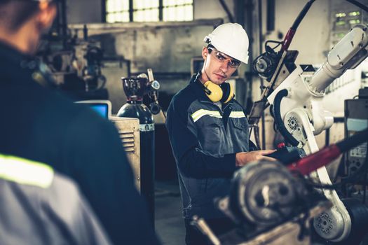 Factory workers working with adept robotic arm in a workshop . Industry robot programming software for automated manufacturing technology .