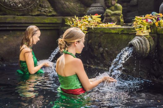 Two women in holy spring water temple in bali. The temple compound consists of a petirtaan or bathing structure, famous for its holy spring water.