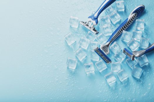 Blue shaving machines in a row on a blue background with ice cubes. The concept of cleanliness and frosty freshness