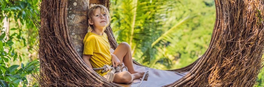 BANNER, LONG FORMAT Bali trend, straw nests everywhere. Child friendly place. Boy tourist enjoying his travel around Bali island, Indonesia. Making a stop on a beautiful hill. Photo in a straw nest, natural environment. Lifestyle. Traveling with kids concept. What to do with children.