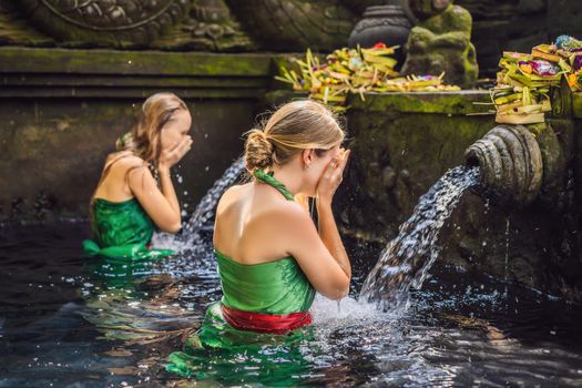 Two women in holy spring water temple in bali. The temple compound consists of a petirtaan or bathing structure, famous for its holy spring water.