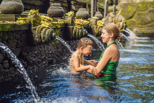 Mother and son in holy spring water temple in bali. The temple compound consists of a petirtaan or bathing structure, famous for its holy spring water.