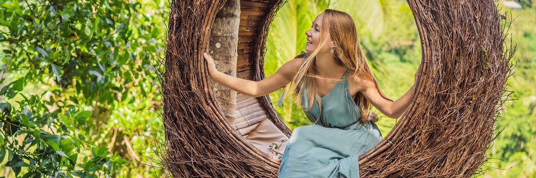 BANNER, LONG FORMAT Bali trend, straw nests everywhere. Young tourist enjoying her travel around Bali island, Indonesia. Making a stop on a beautiful hill. Photo in a straw nest, natural environment. Lifestyle.