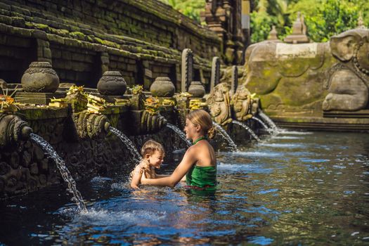 Mother and son in holy spring water temple in bali. The temple compound consists of a petirtaan or bathing structure, famous for its holy spring water.