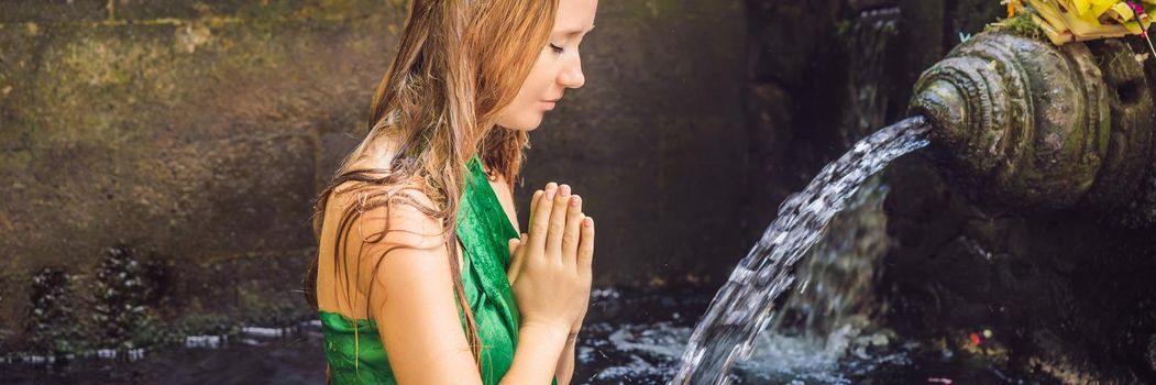 Woman in holy spring water temple in bali. The temple compound consists of a petirtaan or bathing structure, famous for its holy spring water. BANNER, LONG FORMAT