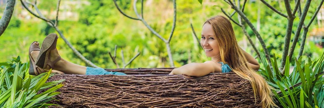 BANNER, LONG FORMAT Bali trend, straw nests everywhere. Young tourist enjoying her travel around Bali island, Indonesia. Making a stop on a beautiful hill. Photo in a straw nest, natural environment. Lifestyle.