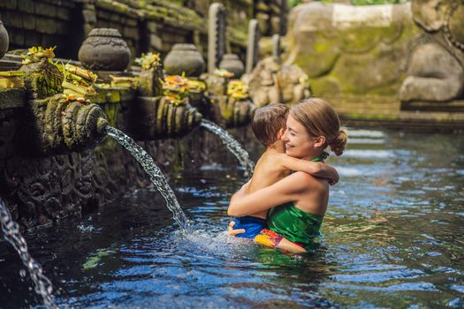 Mother and son in holy spring water temple in bali. The temple compound consists of a petirtaan or bathing structure, famous for its holy spring water.