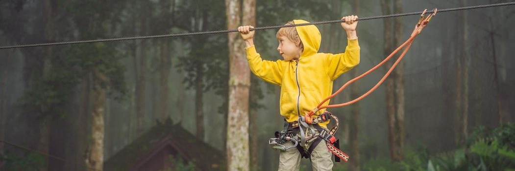 Little boy in a rope park. Active physical recreation of the child in the fresh air in the park. Training for children. BANNER, LONG FORMAT