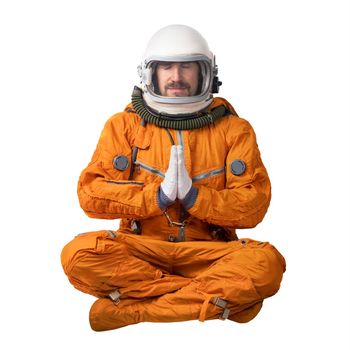 Astronaut wearing orange space suit and space helmet sitting in a lotus yoga pose focused meditating putting his hands together in prayer gesture isolated on a white background. Meditation concept