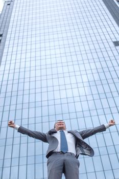 happy young businessman standing on the street in front of the office . photo with copy space