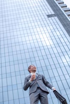 modern business man standing near a tall office building. photo with copy space