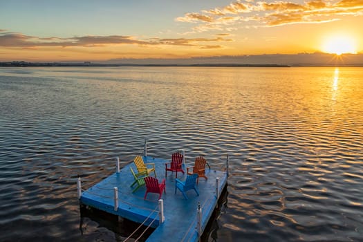 Empty chairs and table on a wooden pier at amazing colorful sunrise in the sea. Time for relax