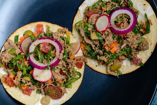 Beef salpicon on corn tostadas. Mexican spicy beef steak salad with carrot, olives, chili, onion, lettuce and radish. Delicious Mexican cuisine