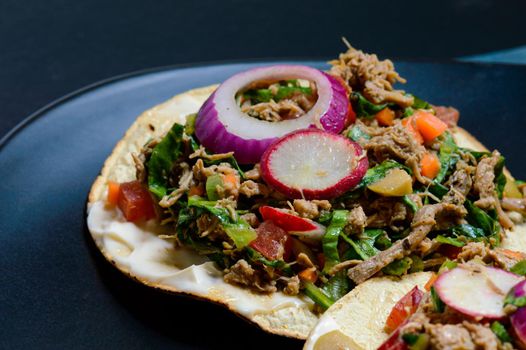 Beef salpicon on corn tostadas. Mexican spicy beef steak salad with carrot, olives, chili, onion, lettuce and radish. Delicious Mexican cuisine