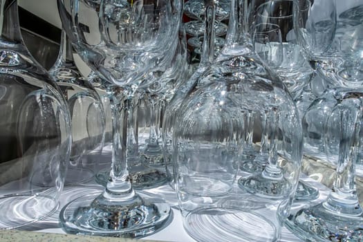 Rows of empty wine glasses close up. Glass goblets on the white table. Restaurant bar concept