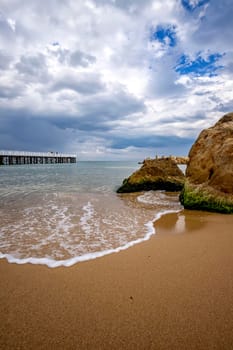 Low angle view of the sea with a pier and big rock on shore