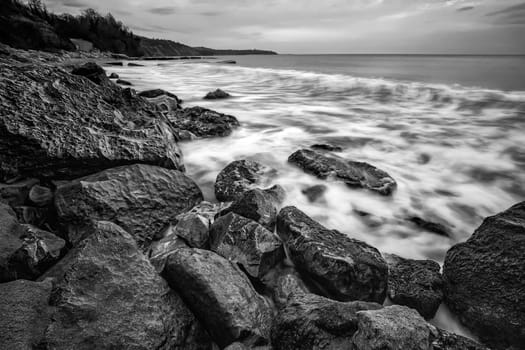 Stunning sunrise over the sea with the rocky sea coast in black and white.