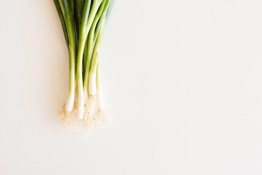 Cropped view of spring onions on white table from above with copy space to right