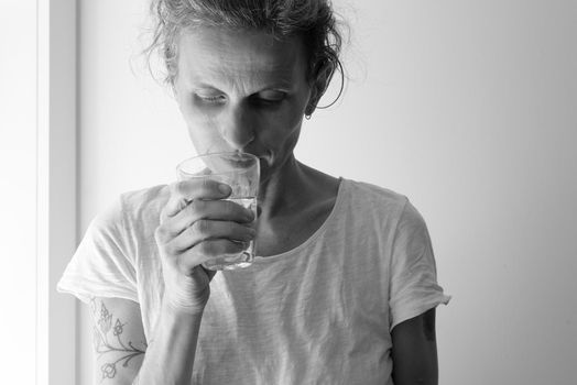 Middle aged woman holding glass and looking down - addiction concept (black and white)