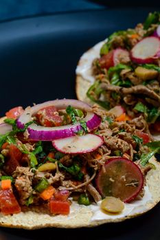 Beef salpicon on corn tostadas. Mexican spicy beef steak salad with carrot, olives, chili, onion, lettuce and radish. Delicious Mexican cuisine