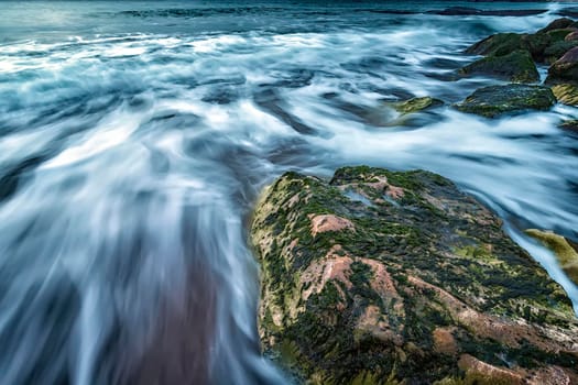 Scenic seascape of a big rock and waves flowing out