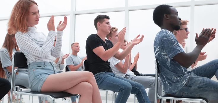 side view. a group of young people sitting in a bright conference room