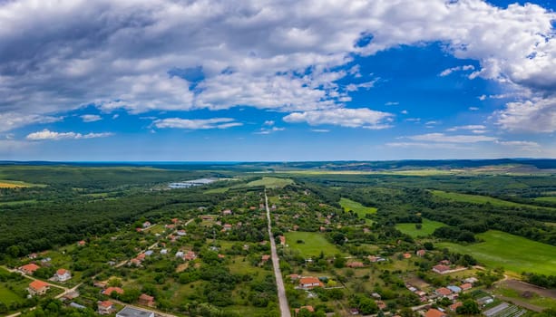 Aerial panorama from a drone of countryside, village, green fields and trees, agriculture concept. Countryside farmland