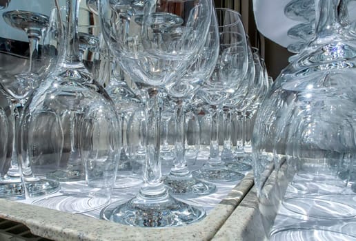 Rows of empty wine glasses close up. Glass goblets on the white table. Restaurant bar concept