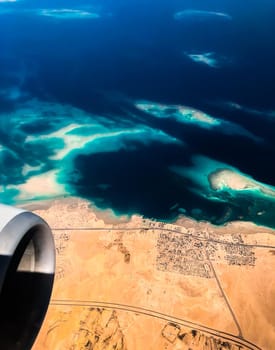 Aerial top view from airplane coastline Egyptian Desert islands. Red sea Sharm Al Sheikh Egypt. Amazing shoot bird eye plane window mountains. Travel concept. turbine aircraft engine flying over ocean