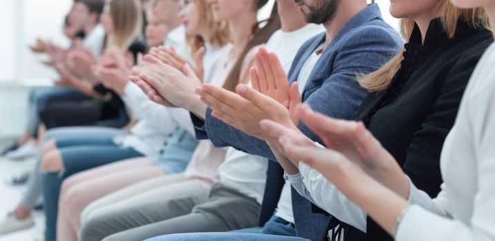 close up. a group of young people sitting in a row applaud together