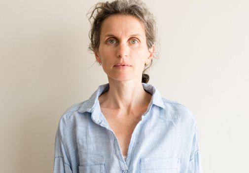 Portrait of natural looking middle aged woman with grey hair and blue shirt