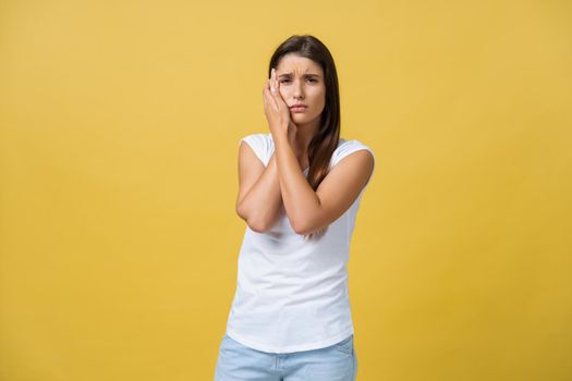 young woman has a toothache, studio photo isolated on a yellow background.
