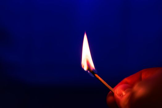 Burning match in right hand, on blue background