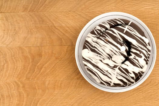 bun covered with chocolate, on a wooden board, close-up