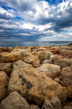 Colorful stones on a shore with stormy clouds at the horizon. Vertical view