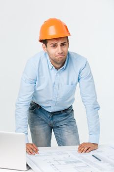 Young man wearing architect outfit and helmet with angry face, negative dislike emotion. Angry and rejection concept.