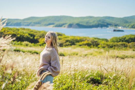 Young beautiful woman in autumn landscape with dry flowers, wheat spikes. Fashion autumn, winter. Sunny autumn, Cozy autumn sweater. fashion photo.