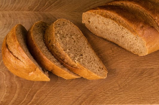 part of a loaf of bread and slices cut from it laid on a wooden board view from the top