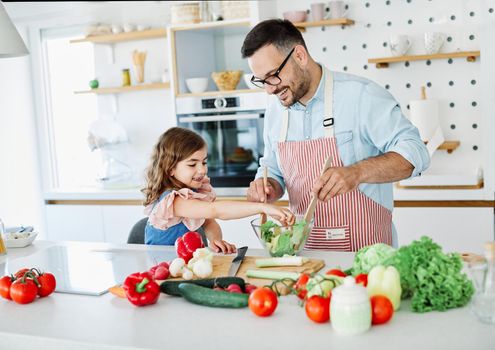 Daughter and father preparing food in the kitchen