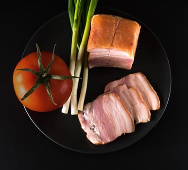 Food, Sliced bacon, tomato green onion, on a black plate, on a black background