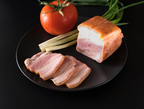 Food, Sliced bacon, tomato green onion, on a black plate, on a black background