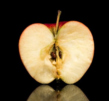 half of a ripe apple on a black background with reflection