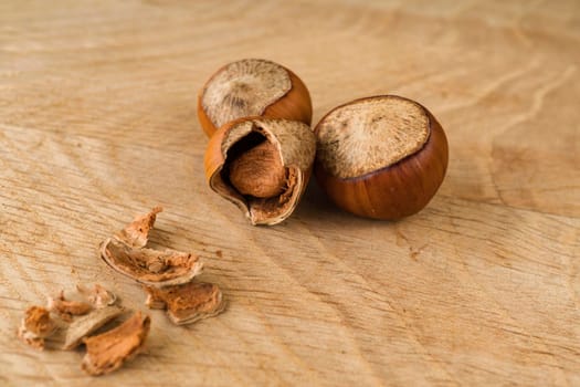 ripe hazelnut, partly separated from the shell and whole in shell, on a wooden board